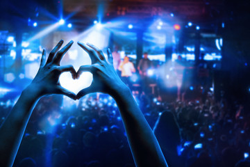 The silhouettes of concert crowd in front of bright stage lights