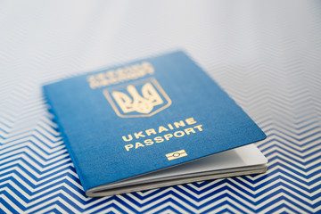 Close up of new ukrainian blue international biometric passport with identification chip on white and blue background. Selective focus