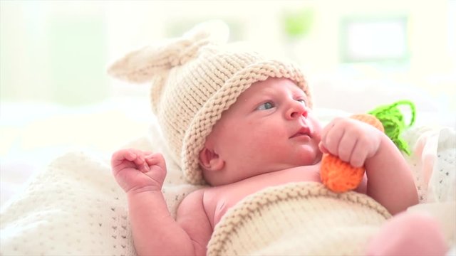 Newborn baby in funny bunny costume in his bed. 4K UHD video 3840X2160