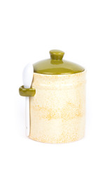 Light ceramic jar with spoon and cover on a white background