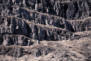 Fototapeta na wymiar Stony hill on the shore of the fjord in eastern Iceland. Toned