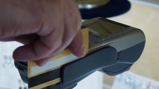 Swiping A Golden Credit Card And Credit Card Terminal POS In A Jewelry Store