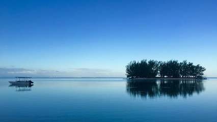 Obraz premium View on a small motor boat and and a small Motu in the lagoon of Moorea in the very early morning