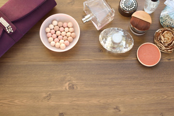 cosmetics on wooden table: powder, lipstick, eye shadow and perfume
