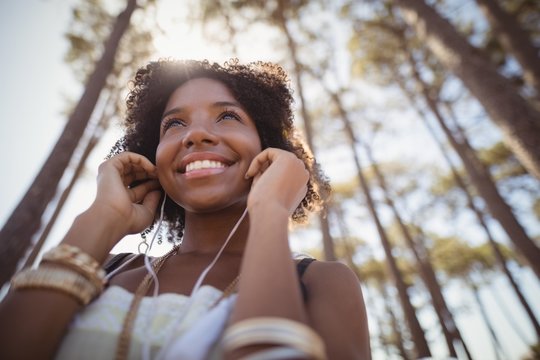 Low angle view of smiling woman listening music