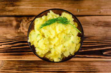 Mashed potatoes in glass bowl on wooden table. Top view