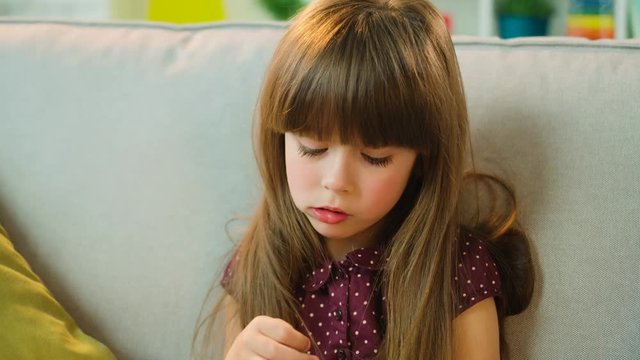 Pretty little girl eating cookies, biscuits and lookind at the camera. Little girl eat ginger bears on the couch at home. Close up