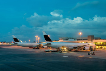 Passenger airplane on runway near the terminal in an airport at night. Airplane parking at departure gate in airport.