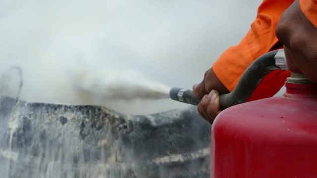 Firefighter putting out a fire with a powder type extinguisher.

