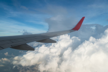 Fototapeta premium Wing of an airplane flying above the clouds. people looks at the sky from the window of the plane, using airtransport to travel.