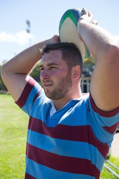Rugby player looking away while throwing ball at field