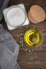 Olive oil with thyme and salt flower on wooden background