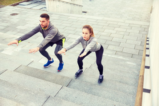 couple doing squats on city street stairs