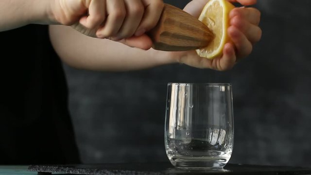 squeezing lemon juice with hand into glass, healthy drink concept