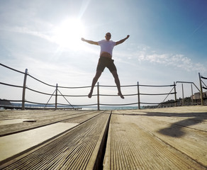 young man jumping happy on pier