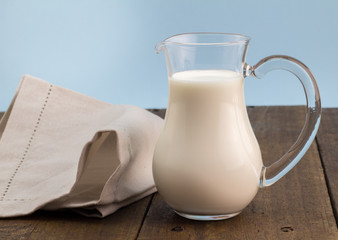Whole milk in glass jug on wooden table