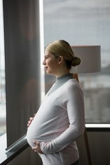 Pregnant businesswoman looking through window in office