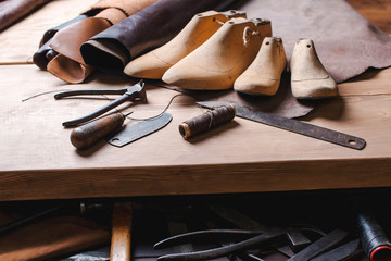 Leather in rolls, cobbler tools and shoe lasts in workshop. Leather craft tools.