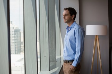 Male executive looking through window in office