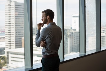 Male executive looking through window in office