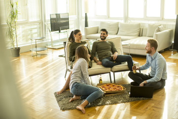 Young people eating pizza and drinking cider in the modern interior