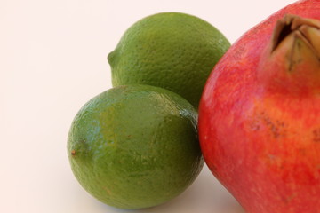 Limetten mit Granatapfel auf weissem Hintergrund isoliert