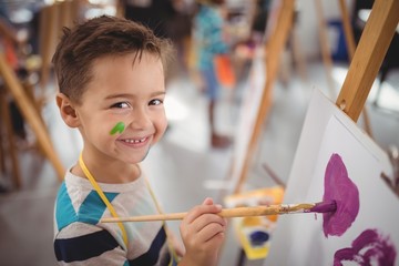 Portrait of happy schoolboy panting on canvas