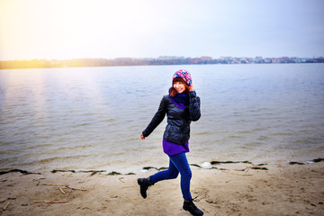 Lifestyle portrait of young Caucasian slim woman runs along beach autumn