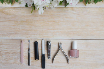 Manicure and pedicure accessories on wooden background with flower frame. Diamond nail file,  stone...