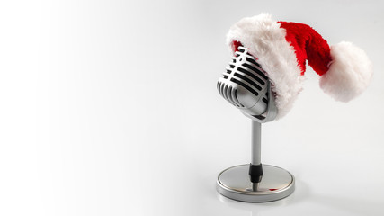 Carols and Christmas music concept with a microphone wearing a santa hat isolated on white with...