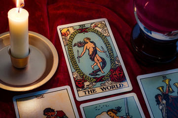 The world tarot card and crystal ball under candle light. Cartomancy is fortune telling using cards, while scrying and clairvoyance is future reading using orbs, both are branches of astrology - obrazy, fototapety, plakaty