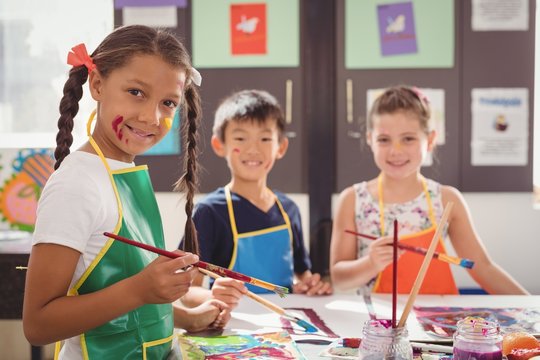 Portrait of happy schoolkids practicing drawing 