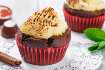Tasty cupcakes with candies and chocolate on light background close up