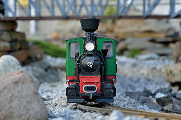 Beautiful realistic train model. Old red and green locomotion with wagons, train driver on metal...