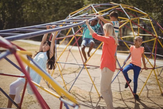 Trainer assisting schoolkids while playing in playground