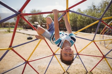 Portrait of happy schoolboy playing on dome climber