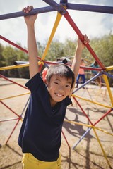 Portrait of happy schoolboy playing on dome climber