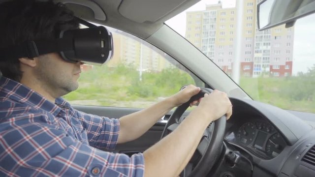 Men driver driving a car rides around the city in the helmet of virtual reality. 360 VR Technology.