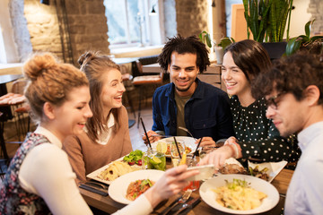 friends with smartphone eating at restaurant