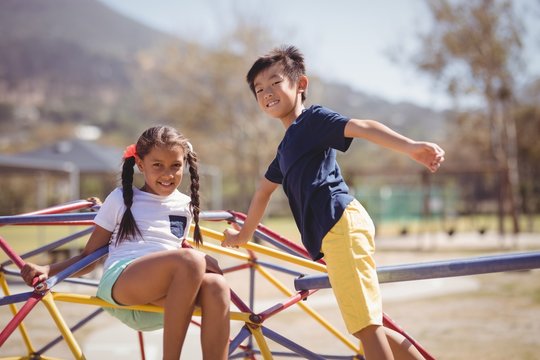 Portrait of happy schoolkids playing on dome climber
