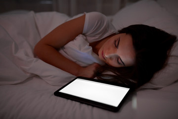 woman with tablet pc sleeping in bed at night