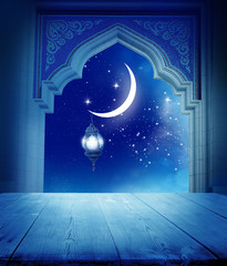 Ramadan Kareem background..Mosque window with shiny crescent moon and wooden table