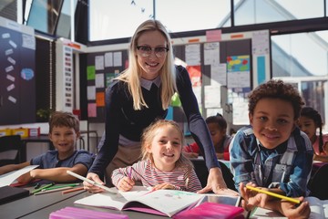 Teacher helping schoolkids with their homework in classroom