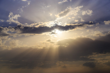 Empty cloudy sky from orange to blue with sun rays during the sunset