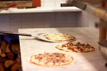 peel taking pizza off table at pizzeria - obrazy, fototapety, plakaty