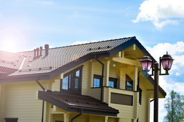 Part of the facade of a wooden house with windows and sun beams