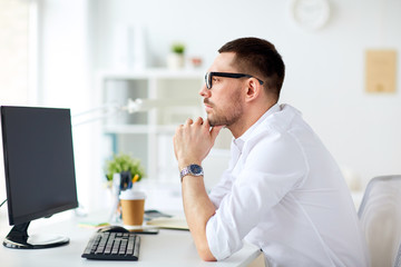 businessman in glasses sitting at office computer