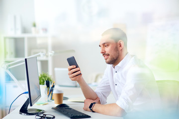 businessman with smartphone and computer at office