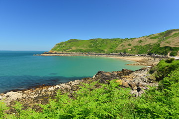 Fototapeta na wymiar Giffard Bay, Jersey, U.K. Wide angle image of a picturesque beach with a teal sea.