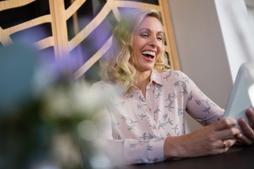 Cheerful businesswoman using digital tablet in cafe